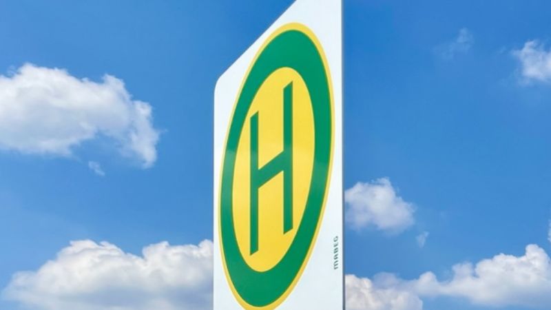 Der Rheinhafen Orsoy im Überflug aus der Luft, mit einem Schiff, das beladen wird. Haltestellenschild vor blauem Himmel