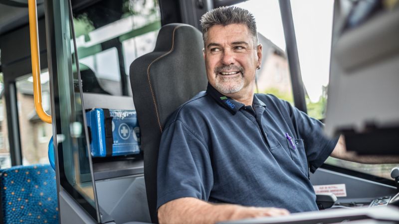 Ein Busfahrer am Steuer. Ein Busfahrer der NIAG am Steuer lächelt